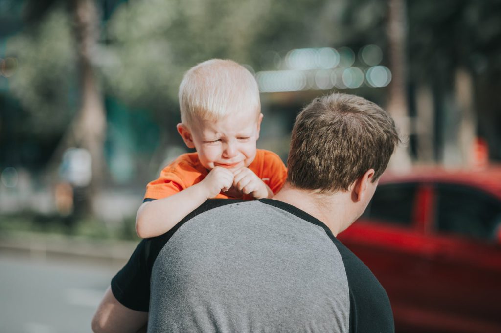 Surviving Parental Burnout with a Smile (or at Least a Smirk) man carrying child